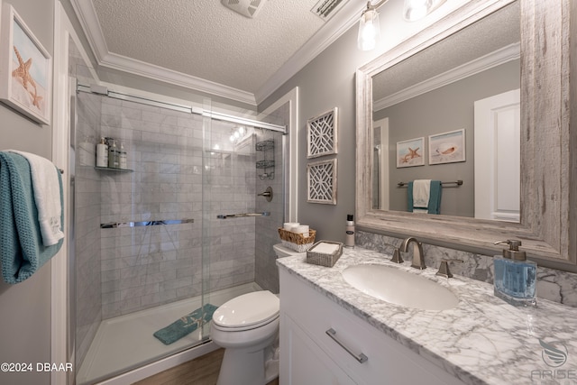 bathroom with a textured ceiling, a shower with door, and ornamental molding