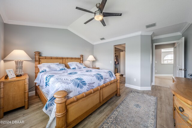 bedroom with light hardwood / wood-style floors, a spacious closet, lofted ceiling, and ceiling fan