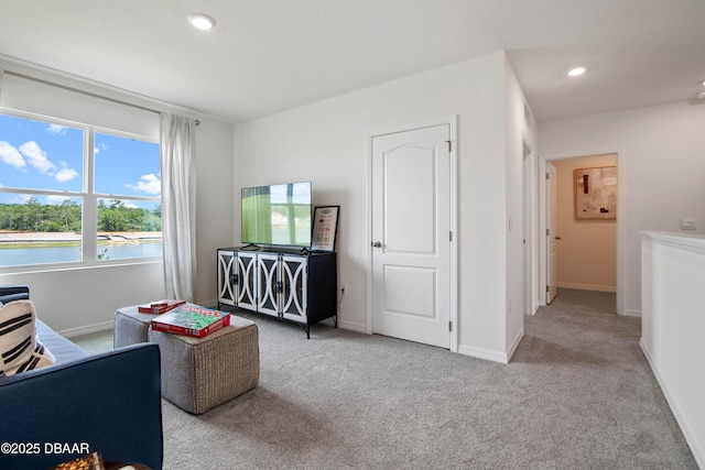 living area with light colored carpet and a water view