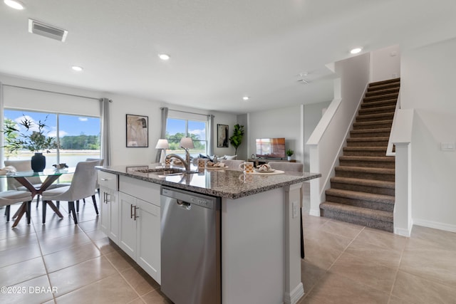 kitchen featuring sink, white cabinets, dark stone counters, stainless steel dishwasher, and a center island with sink