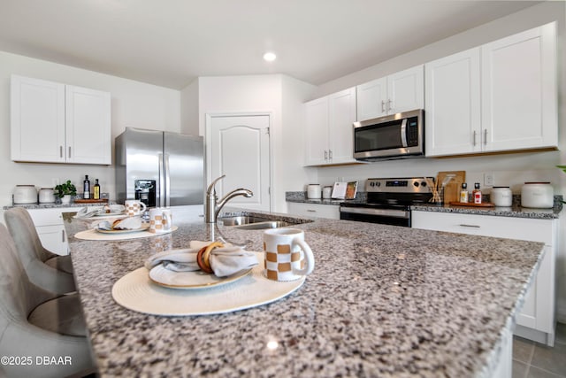 kitchen featuring light stone countertops, appliances with stainless steel finishes, sink, and white cabinets