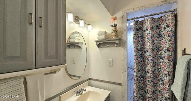 full bath featuring a shower with curtain, a wainscoted wall, and vanity