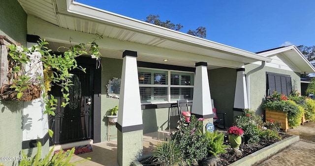 entrance to property with a porch and stucco siding