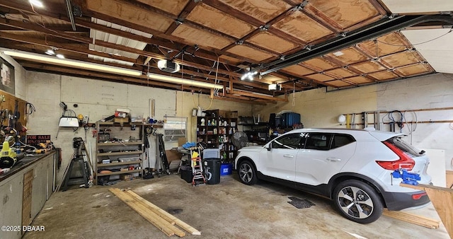 garage with a garage door opener, a workshop area, and concrete block wall
