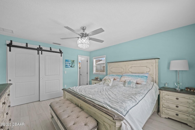 1942 N Daytona Ave, Flagler Beach, FL 32136 - bedroom with a barn door, a closet, light wood finished floors, and a ceiling fan