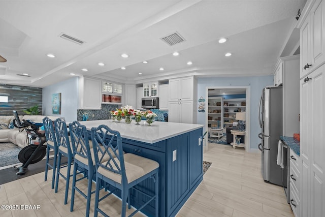 1942 N Daytona Ave, Flagler Beach, FL 32136 - kitchen featuring stainless steel appliances, white cabinetry, a breakfast bar, decorative backsplash, and recessed lighting
