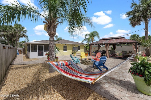 1942 N Daytona Ave, Flagler Beach, FL 32136 - back of house with an outdoor fire pit, a sunroom, a gazebo, a patio, and a fenced backyard