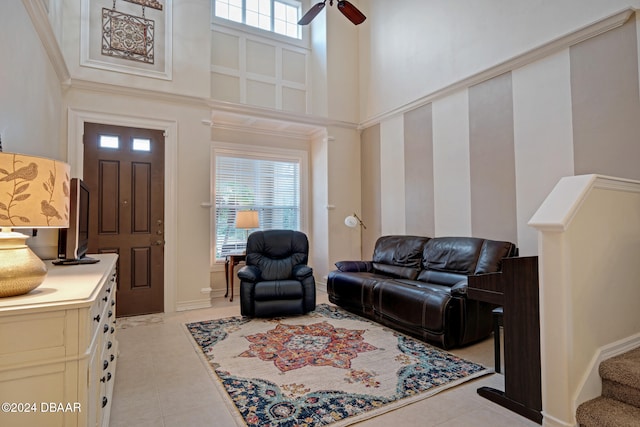 tiled living room featuring ceiling fan, a towering ceiling, and a healthy amount of sunlight