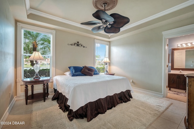 tiled bedroom featuring ceiling fan, a raised ceiling, multiple windows, and ensuite bath