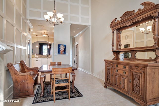 tiled dining room with ornamental molding, a high ceiling, and a chandelier