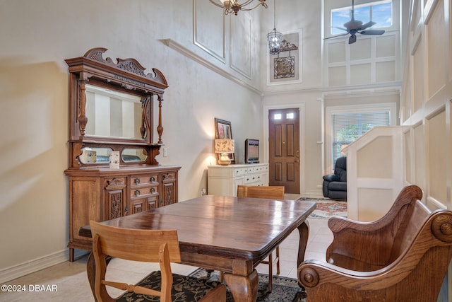 dining area with light tile patterned floors, a towering ceiling, and ceiling fan