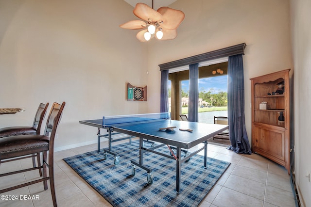 recreation room featuring ceiling fan, light tile patterned flooring, and a towering ceiling