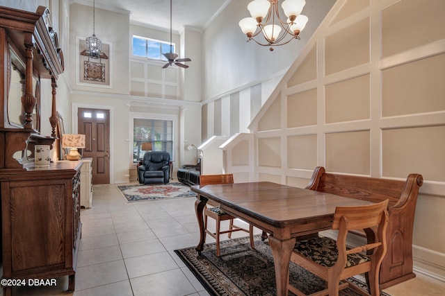 dining area with ceiling fan with notable chandelier, light tile patterned floors, a towering ceiling, and ornamental molding