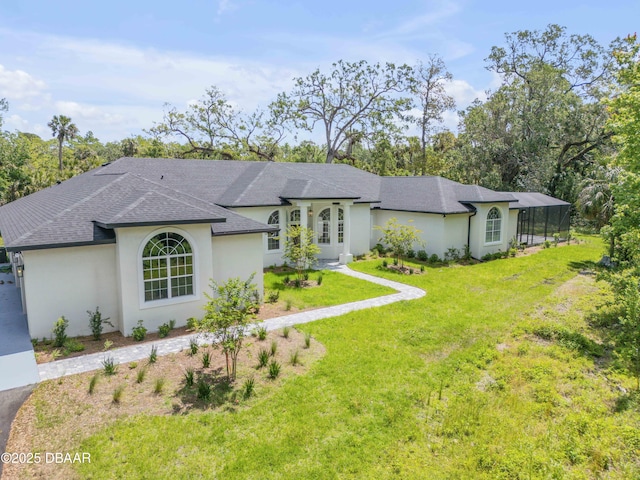 view of front of property with glass enclosure, roof with shingles, a front yard, and stucco siding