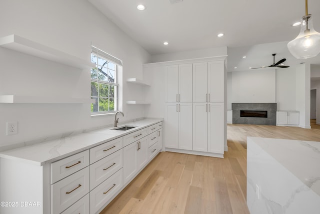 kitchen with a sink, recessed lighting, light wood-style floors, white cabinetry, and open shelves