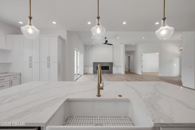 kitchen featuring a sink, light wood-type flooring, open floor plan, recessed lighting, and white cabinetry