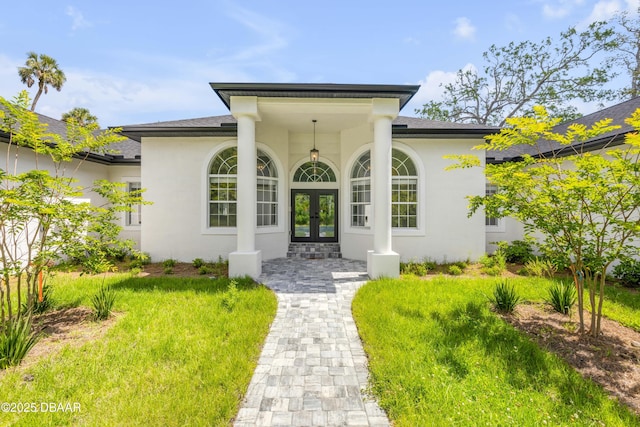 doorway to property featuring a shingled roof, french doors, and stucco siding