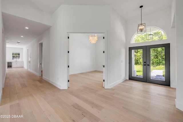 entrance foyer with recessed lighting, light wood finished floors, an inviting chandelier, french doors, and baseboards