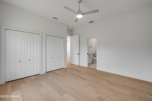 unfurnished bedroom featuring light wood finished floors, baseboards, multiple closets, and visible vents