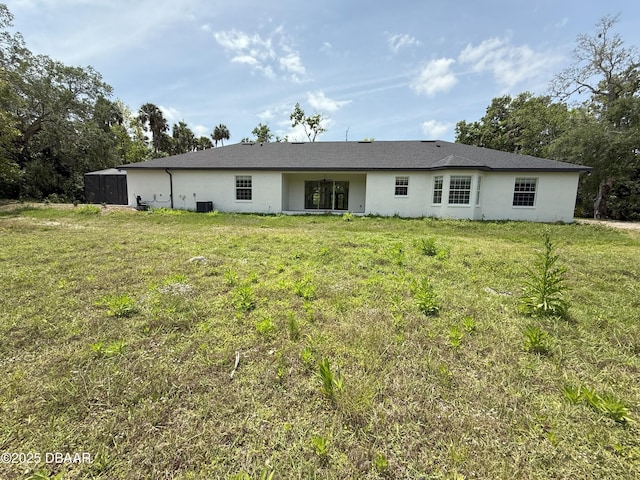 rear view of property with a lawn, central AC, and stucco siding