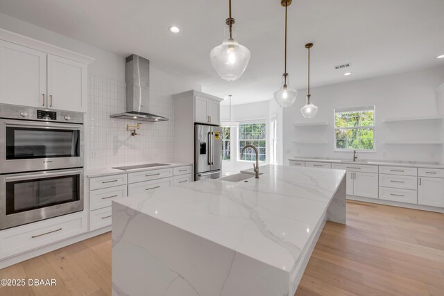 kitchen with wall chimney exhaust hood, a sink, visible vents, open shelves, and appliances with stainless steel finishes