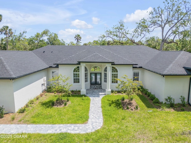 ranch-style home with french doors, roof with shingles, a front lawn, and stucco siding
