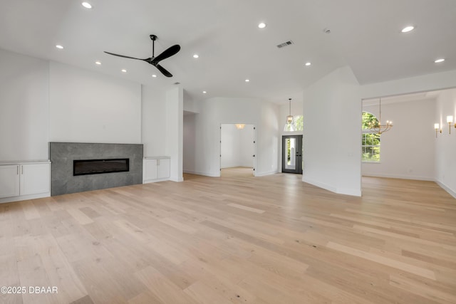 unfurnished living room featuring ceiling fan with notable chandelier, light wood finished floors, a fireplace, visible vents, and recessed lighting