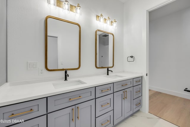 bathroom featuring double vanity, baseboards, and a sink