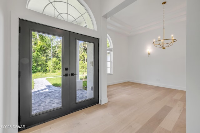 entryway featuring baseboards, a notable chandelier, french doors, and wood finished floors