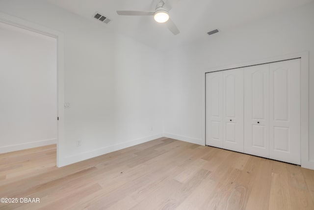 unfurnished bedroom with light wood finished floors, baseboards, visible vents, and a closet