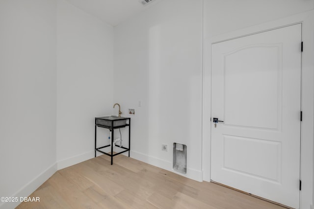 clothes washing area featuring light wood-style flooring, baseboards, hookup for a washing machine, electric dryer hookup, and laundry area