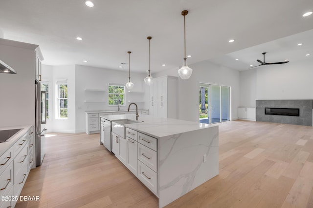 kitchen with recessed lighting, black electric cooktop, open shelves, stainless steel refrigerator, and a sink
