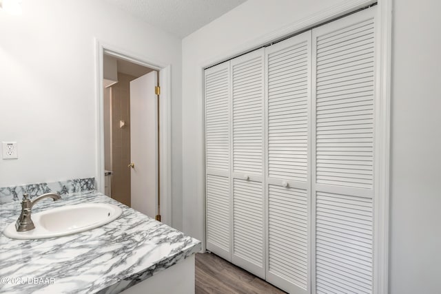 bathroom with a textured ceiling, vanity, and hardwood / wood-style floors