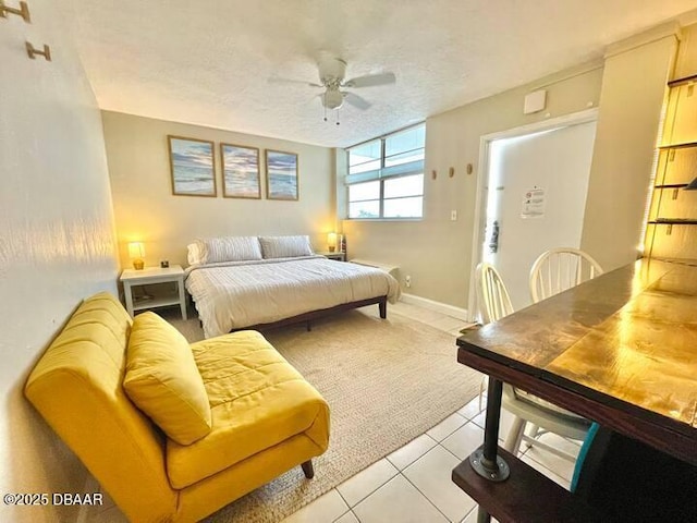 bedroom featuring ceiling fan, baseboards, a textured ceiling, and light tile patterned flooring