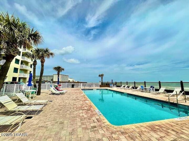 view of swimming pool featuring a patio and a water view