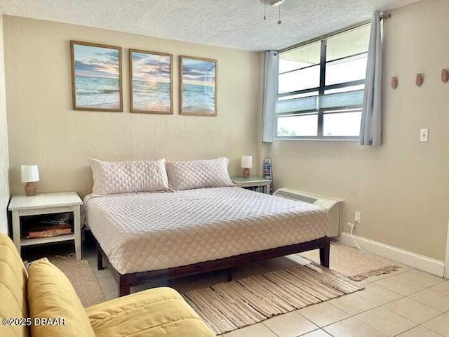 bedroom featuring light tile patterned floors, baseboards, and a textured ceiling