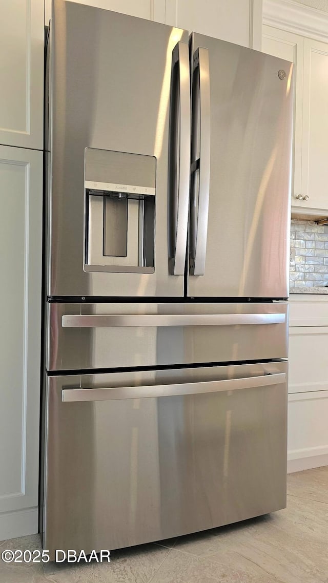 details with light hardwood / wood-style flooring, backsplash, stainless steel fridge, and white cabinets