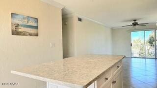 kitchen featuring white cabinetry, ceiling fan, crown molding, and a kitchen island