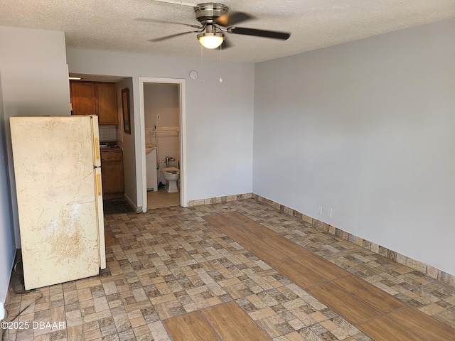 unfurnished room featuring ceiling fan, washer / clothes dryer, and a textured ceiling