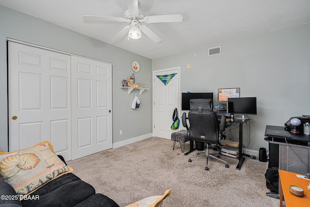 carpeted office space featuring baseboards, visible vents, and a ceiling fan