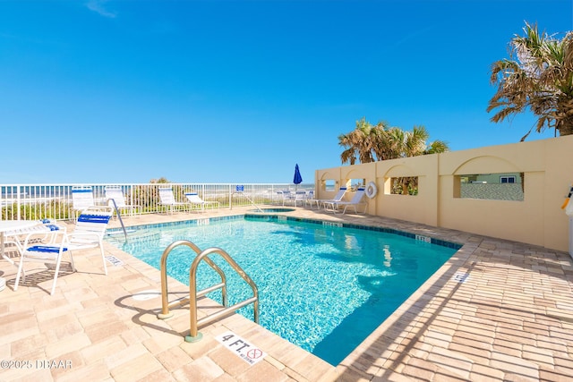 pool featuring a water view, fence, and a patio