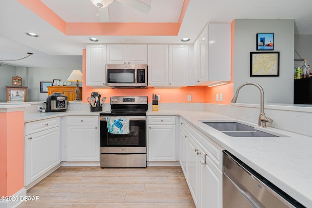 kitchen with stainless steel appliances, a sink, and white cabinets