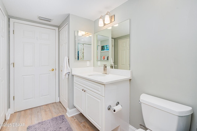 full bath with visible vents, vanity, toilet, and wood finished floors