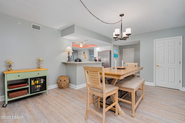 dining area with light wood-style flooring, visible vents, baseboards, and ceiling fan with notable chandelier