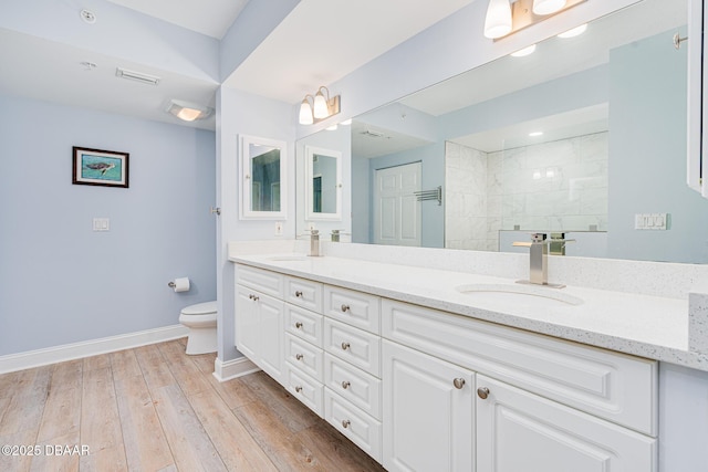bathroom featuring toilet, baseboards, a sink, and wood finished floors