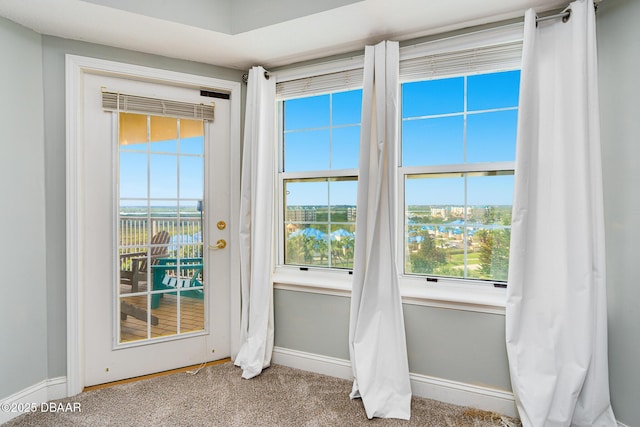 doorway with carpet floors and baseboards