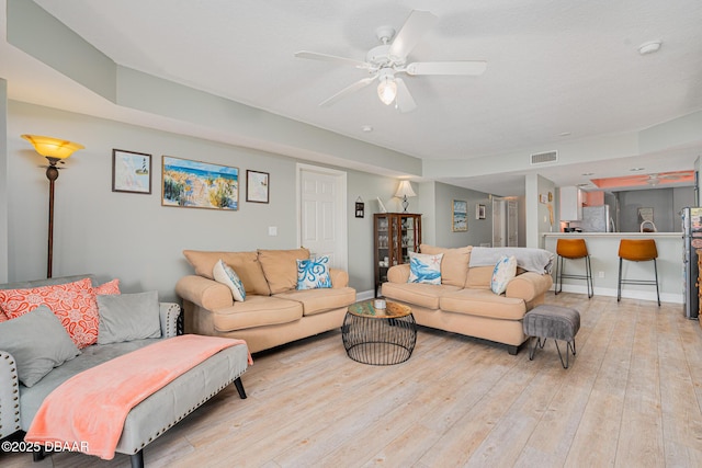 living room featuring light wood-style floors, visible vents, baseboards, and a ceiling fan