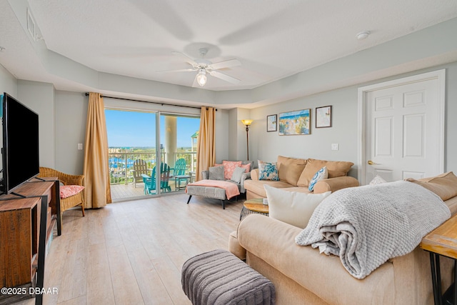 living room with visible vents, a ceiling fan, and light wood-style floors