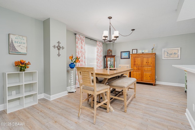 dining room featuring a chandelier, light wood finished floors, and baseboards