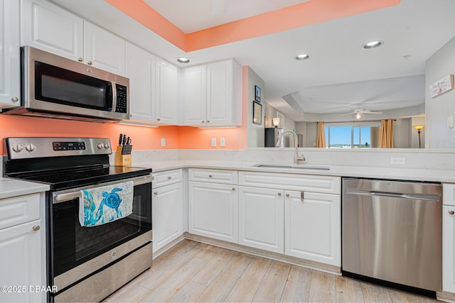 kitchen with stainless steel appliances, light countertops, a sink, and white cabinetry